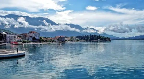 Widok na spokojną kotor zatoka z górami w tle i miasteczkiem nad brzegiem.