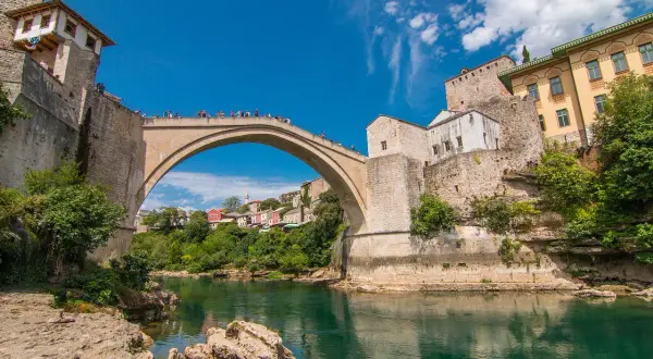 Mostar, Bośnia i Hercegowina. Słynny Stary Most nad rzeką Neretwą. Turyści podziwiają widoki, a ceny pamiątek są przystępne.