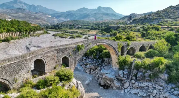 Kamienna, zabytkowa konstrukcja w Szkodrze, Albania, z kobietą w fioletowej sukni na szczycie.