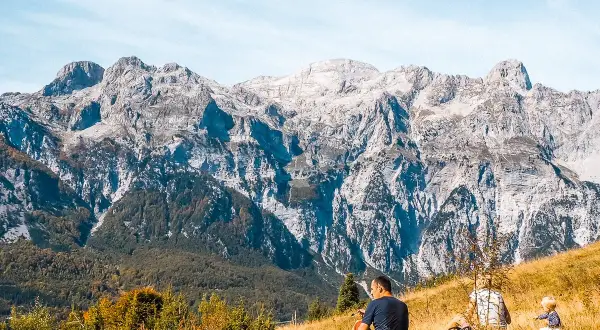 Rodzina odpoczywa na trawiastym zboczu, podziwiając majestatyczne albania góry.