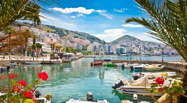 Albania, gdzie na wakacje? Widok na port z łodziami i kolorowe budynki na wzgórzu. Idealne miejsce na wypoczynek.