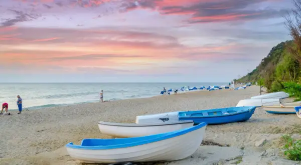 Zachód słońca nad Morzem Czarnym, łodzie na plaży. Zastanawiasz się, ile kosztuje lot do Bułgarii?