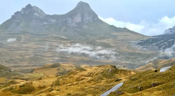 Górzyste krajobrazy Durmitor National Park, z krętymi drogami i mgłą unoszącą się nad złotymi wzgórzami.