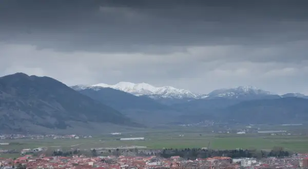 Widok na miasto Korce w Albanii z ośnieżonymi górami w tle.