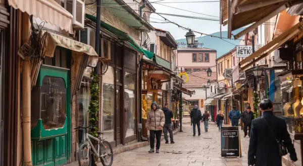Ulica w Skopje, gdzie można kupić pamiątki za walutę Macedonii Północnej. Widać ludzi spacerujących między sklepami.