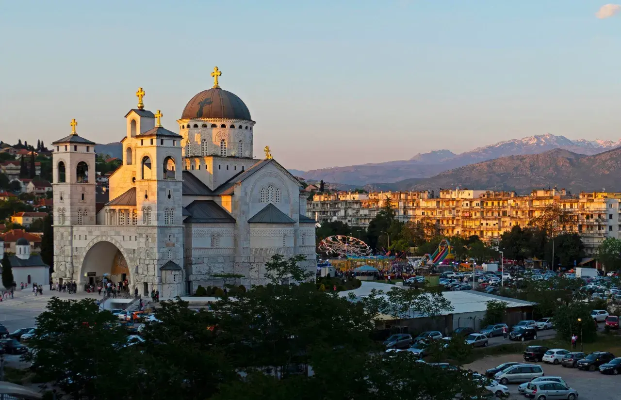 Podgorica atrakcje: monumentalna cerkiew i wesołe miasteczko w blasku zachodzącego słońca.