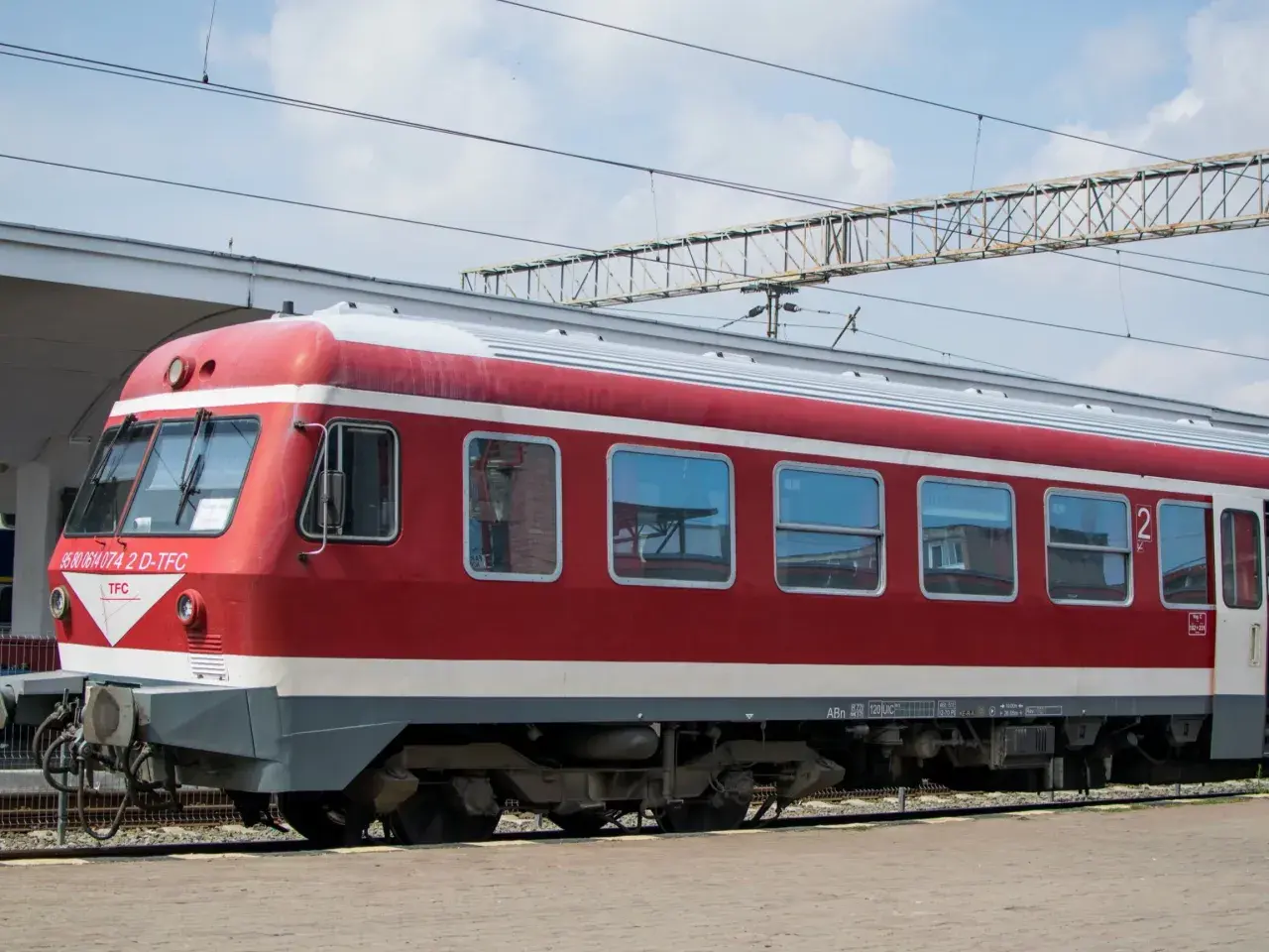 Czerwono-biały pociąg stoi na torach, gotowy do podróży. Czy to właśnie ten pociąg do Bułgarii?