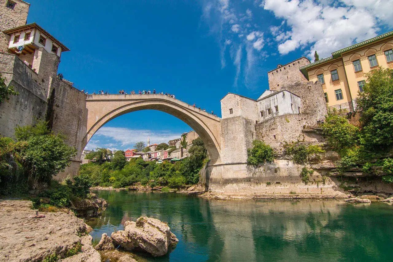 Mostar, Bośnia i Hercegowina. Słynny Stary Most nad rzeką Neretwą. Turyści podziwiają widoki, a ceny pamiątek są przystępne.