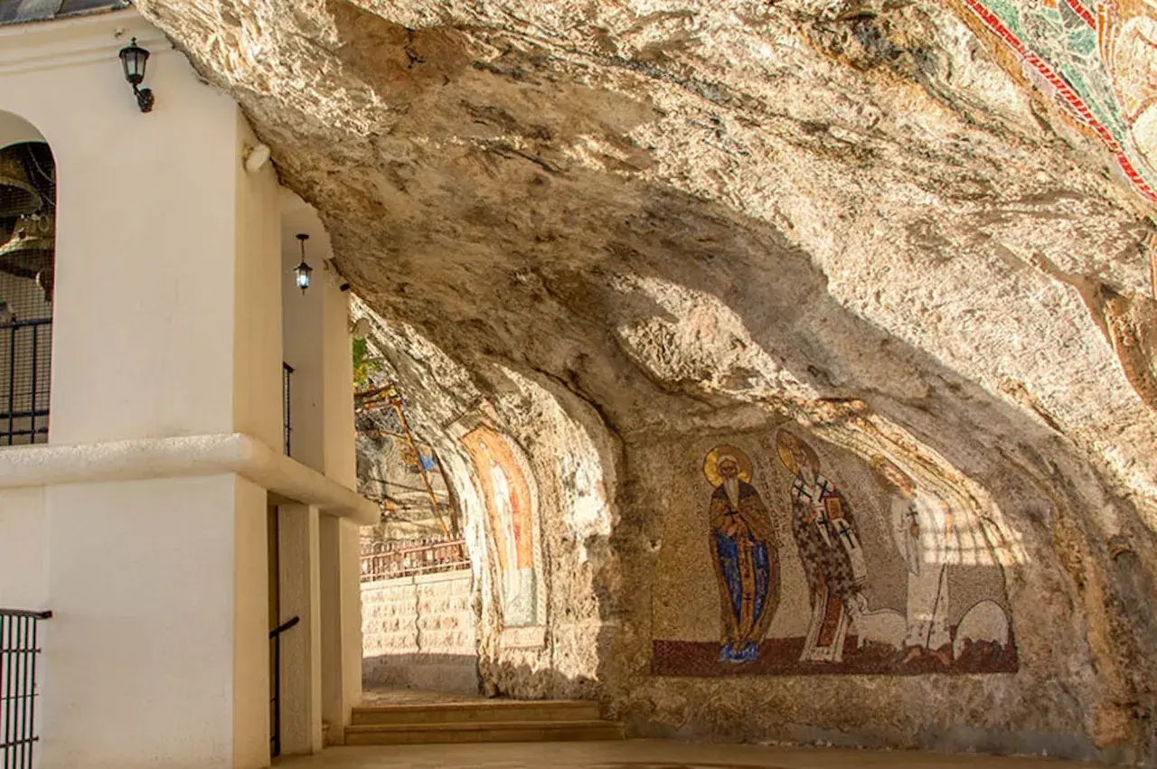 W skalnych niszach monasteru Ostrog widnieją mozaiki świętych. Biała architektura kontrastuje z surową skałą.