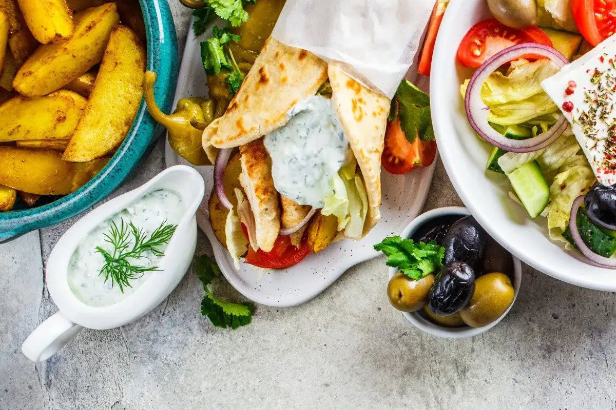 Pyszne greckie przepisy: gyros z kurczakiem, frytki, sałatka grecka i sos tzatziki.