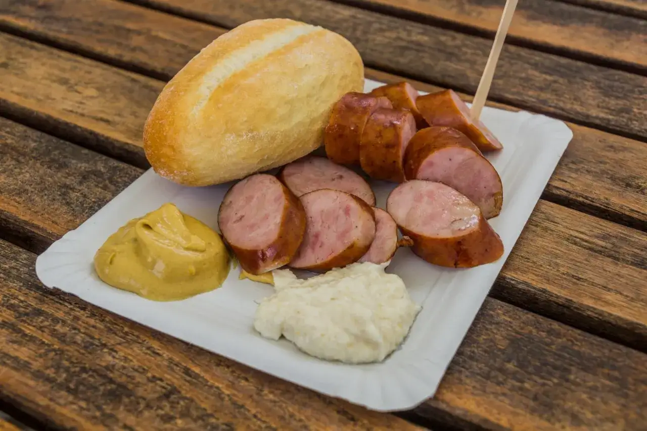 Kiełbasa, bułka i musztarda na talerzyku – klasyka kuchni słoweńskiej.
