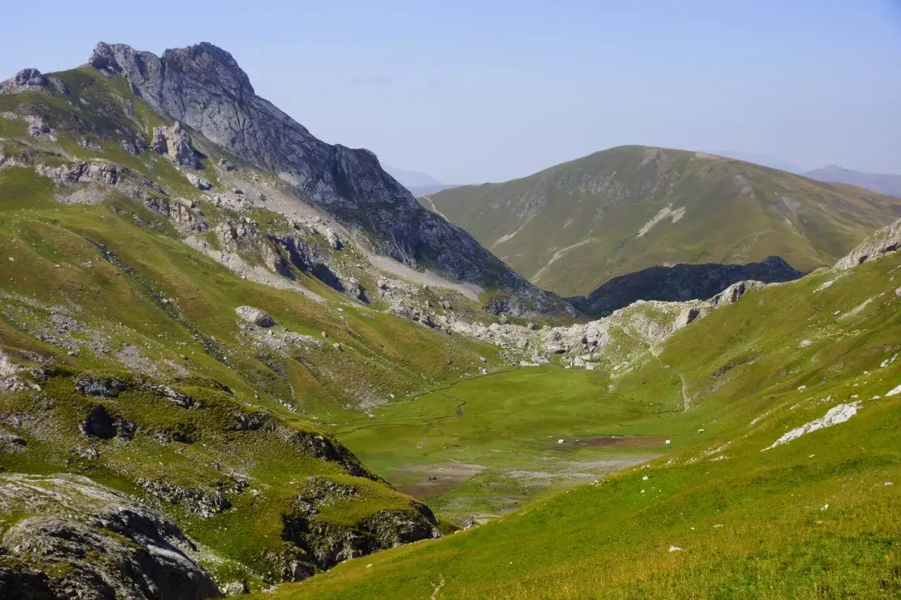 Zielone, skaliste albania góry z doliną i strumieniem.