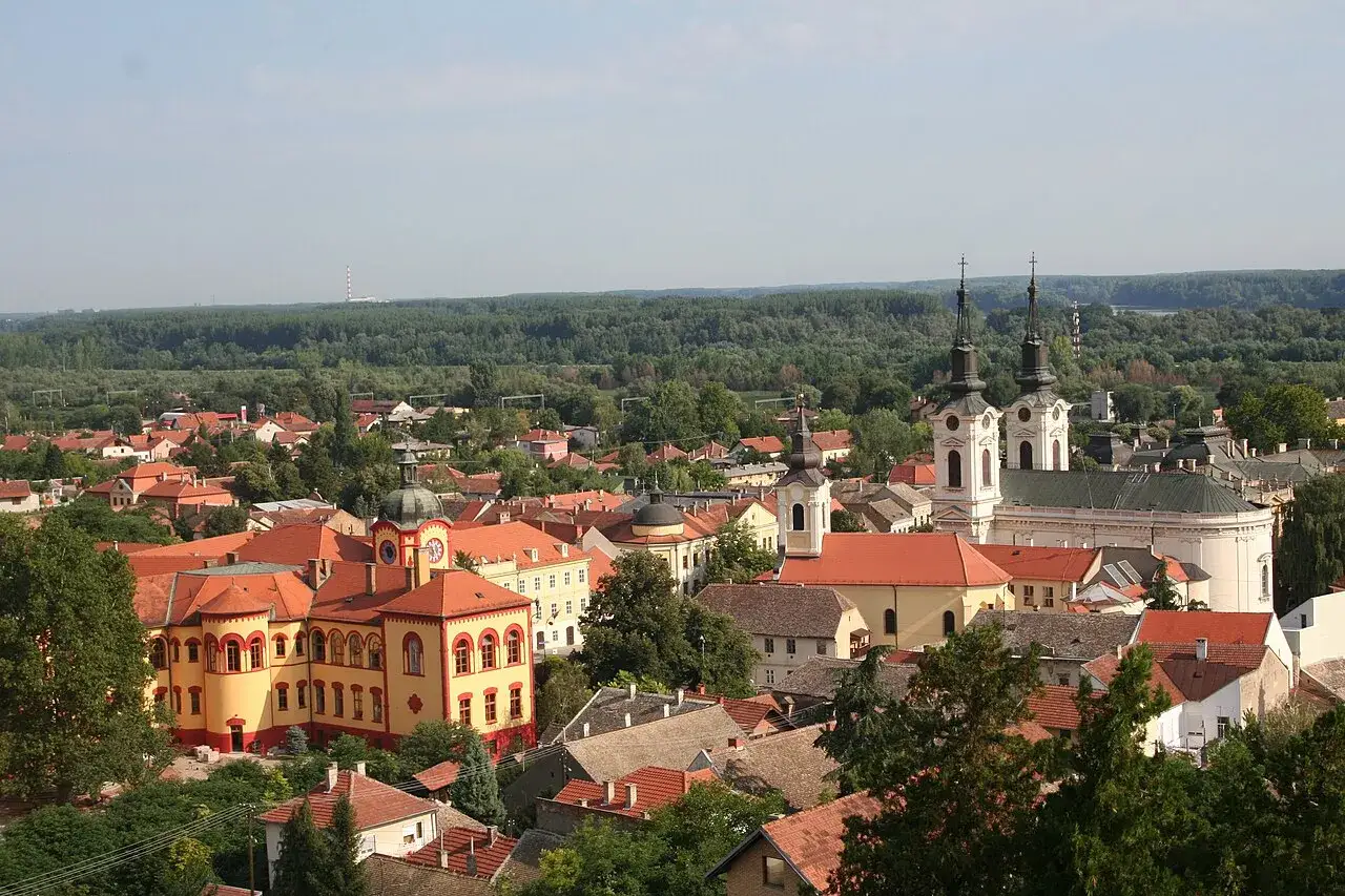 Widok na Sremski Karlovci z charakterystycznymi czerwonymi dachami, kościołami i zielonymi drzewami.