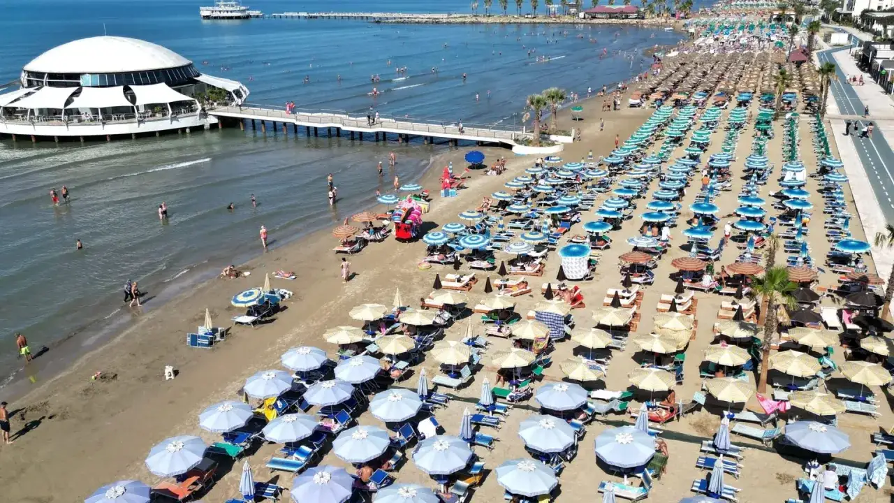 Tłum ludzi odpoczywa na słonecznej durres plaży, rozłożone leżaki i parasole tworzą kolorowy dywan.