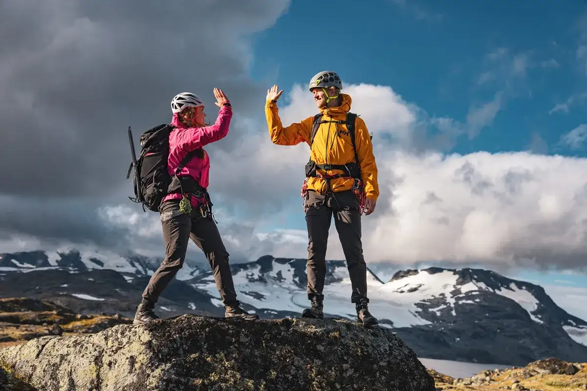 Dwóch alpinistów świętuje sukces na szczycie, pokonując przeklęte góry.