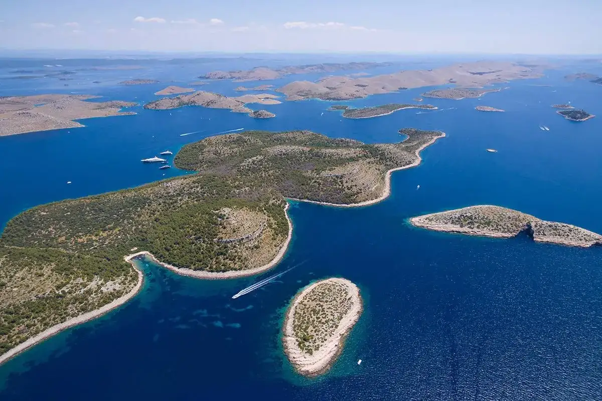 Archipelag wysp w parku narodowym Kornati z turkusową wodą i zielonymi wzgórzami. Widoczne łodzie i jachty.