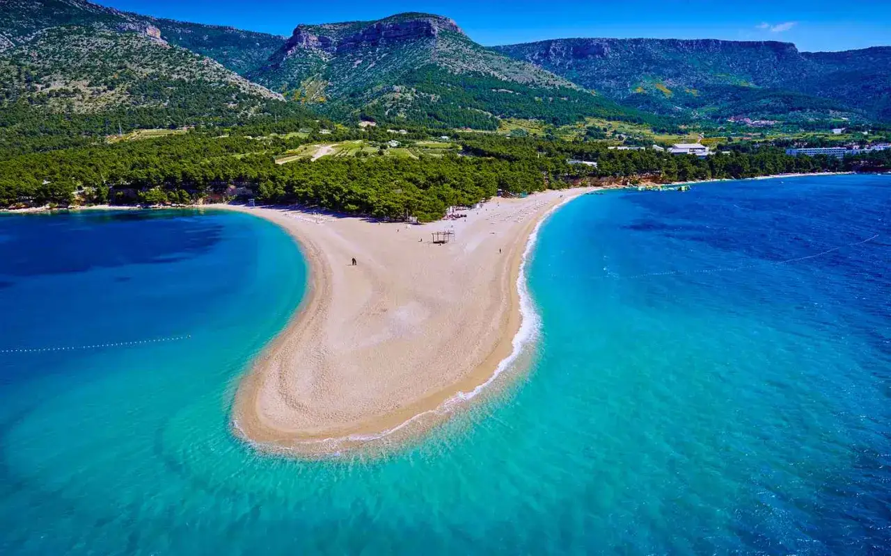 Zlatni Rat, znana jako brela plaża, to unikatowy cypel otoczony turkusowym morzem, z zielonymi wzgórzami w tle.