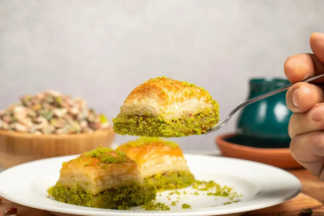Słodka baklava, klasyczne tureckie jedzenie, posypana pistacjami, podana na talerzu.
