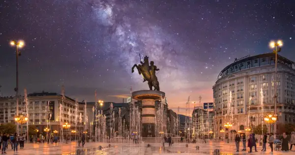Skopje atrakcje nocą: pomnik Wojownika na koniu, fontanny i Droga Mleczna nad miastem.