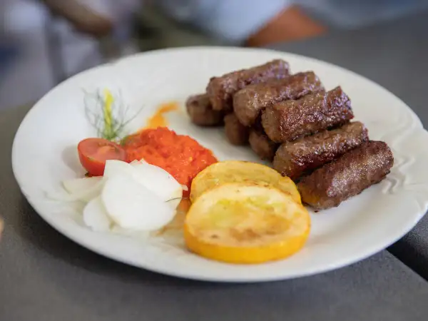 Cevapi, klasyka kuchni słoweńskiej, podane z ajvarem, cebulą i pomidorem.