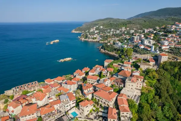Widok na miasto Ulcinj z lotu ptaka. Czerwone dachy, kamienne budynki i błękitne morze tworzą malowniczy krajobraz. To miejsce pełne atrakcji.