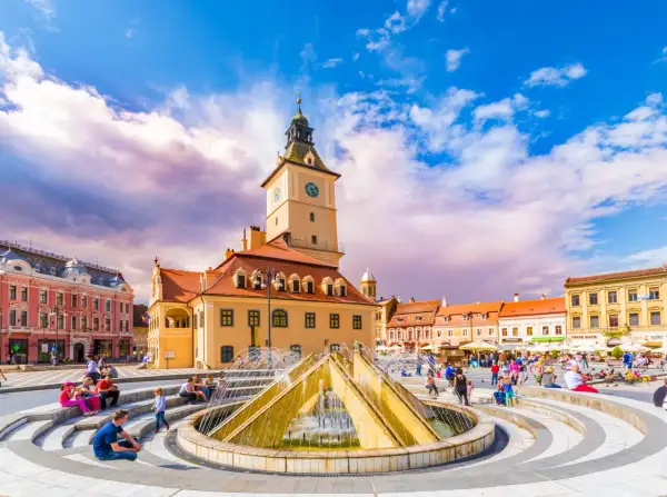 Rynek w Braszowie w Rumunii, z ratuszem i fontanną, tętni życiem.