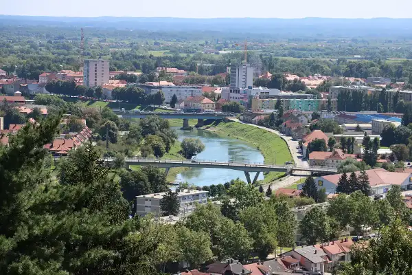 Widok na miasto Karlovac w Chorwacji z rzeką przecinającą krajobraz i mostami łączącymi brzegi.