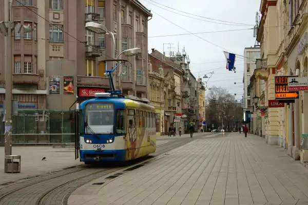 Tram w centrum Osijek, Chorwacja. W tle kamienice i sklepowe witryny.