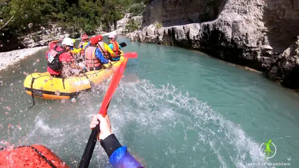 Rafting w malowniczym kanionie w Albanii. Grupa turystów w żółtej łodzi pokonuje rwący nurt rzeki, otoczeni skalnymi ścianami.