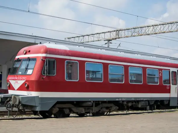 Czerwono-biały pociąg stoi na torach, gotowy do podróży. Czy to właśnie ten pociąg do Bułgarii?