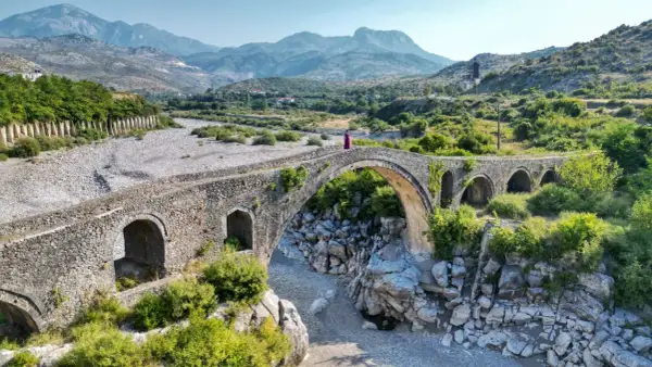 Kamienna, zabytkowa konstrukcja w Szkodrze, Albania, z kobietą w fioletowej sukni na szczycie.