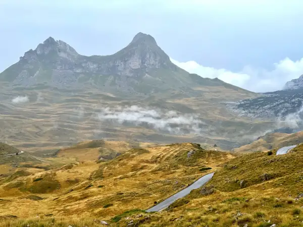 Górzyste krajobrazy Durmitor National Park, z krętymi drogami i mgłą unoszącą się nad złotymi wzgórzami.