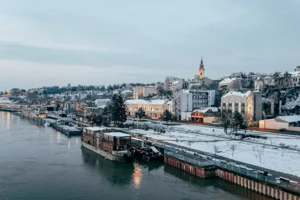 Zimowy Belgrad nad Dunajem, z ośnieżonymi budynkami i statkami. Czy Serbia jest bezpieczna? Widok sugeruje spokojne miasto.